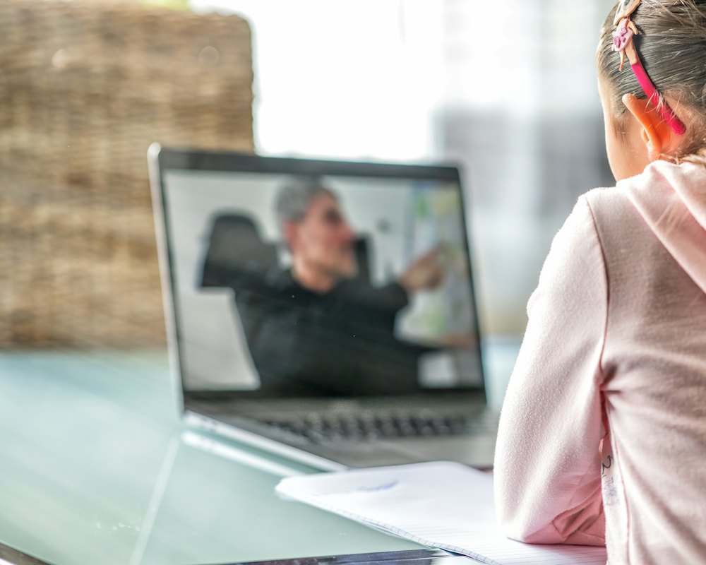 A girl at home following her teacher on a laptop screen